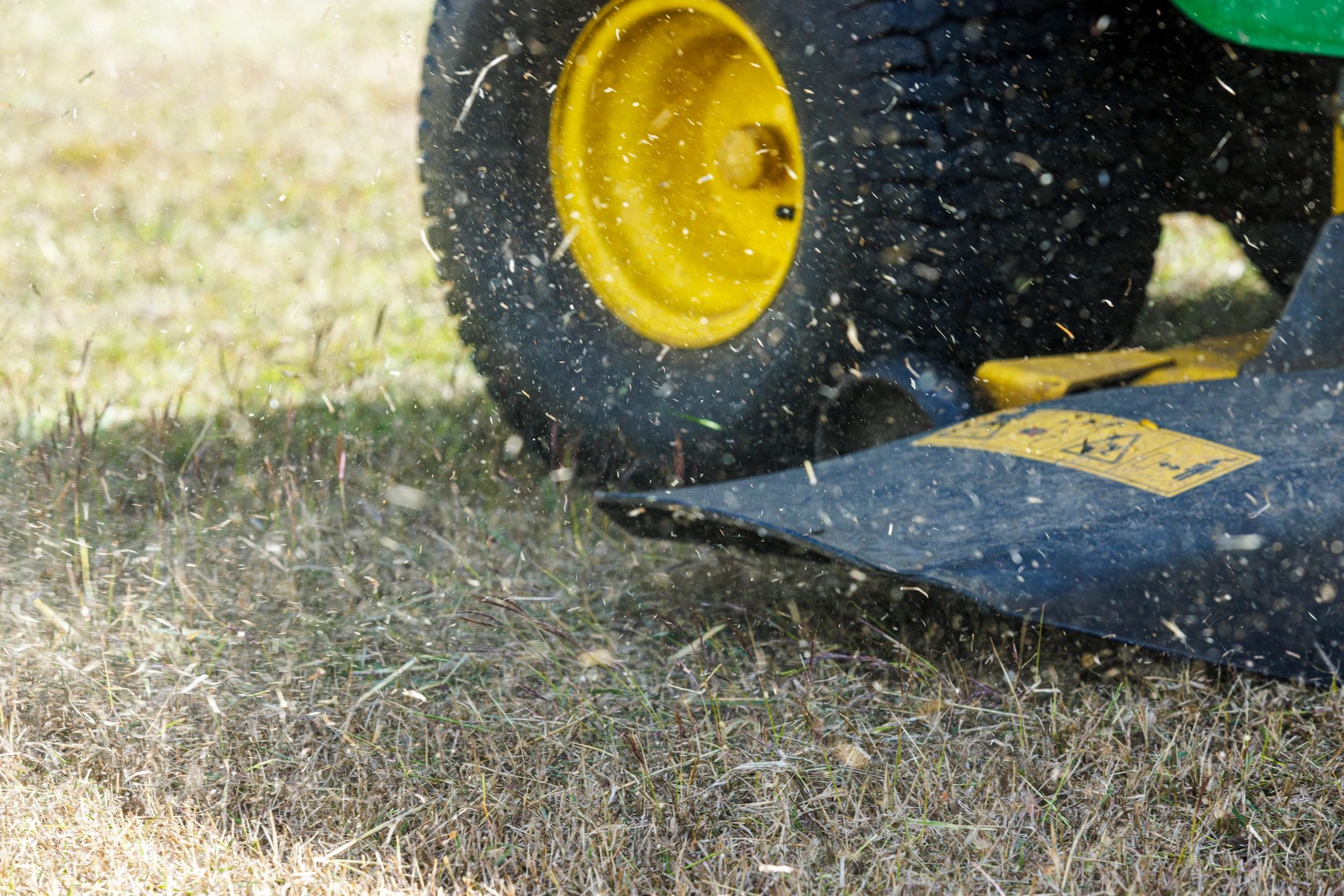 Close-up of a riding lawn mower cutting grass